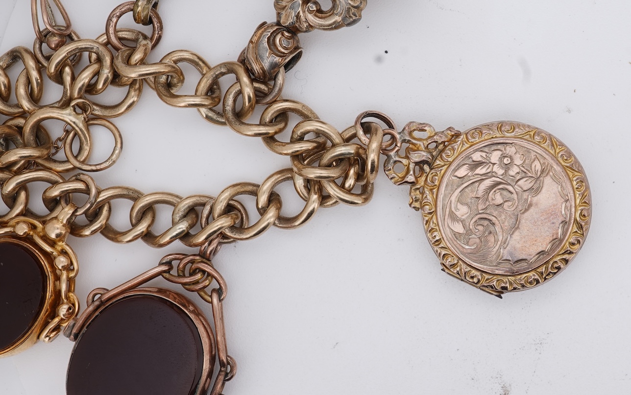 A 1970's 9ct gold curb link charm bracelet, with 9ct gold heart shaped clasp, hung with seven assorted gold or gilt metal mounted charms including six chalcedony set fob seals, gross weight 73 grams.
